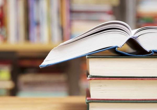 Stack of books with an opened book laying on top.